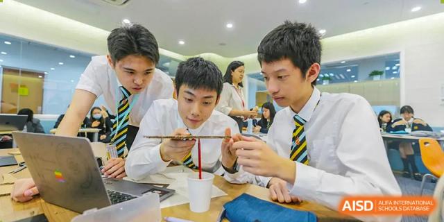 Huili School Shanghai students in school uniforms collaborating on assembling a small model or engineering structure.
