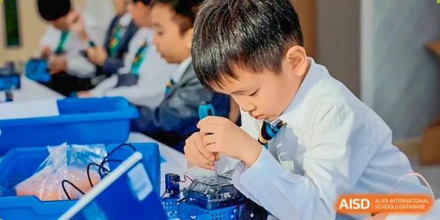 A Huili School Shanghai student in a lab coat carefully working with electronics and small components.