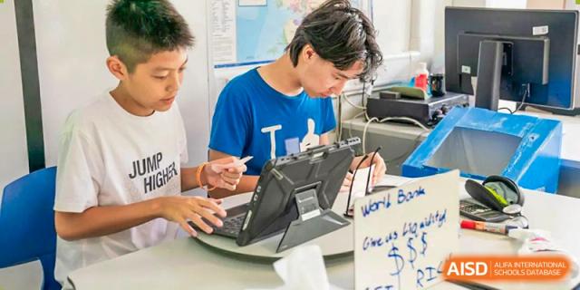 Huili School Shanghai students using laptops and digital devices for coding or a technology project.