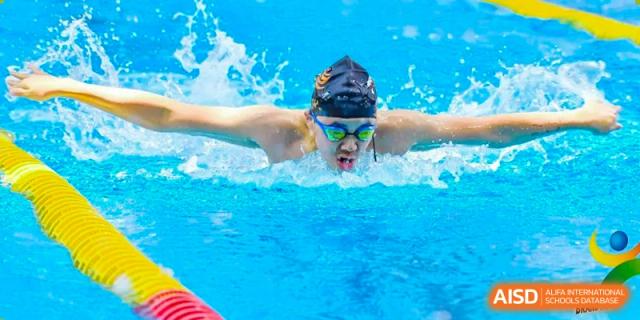 Close-up of a Huili School Shanghai swimmer using the butterfly stroke during a race, looking directly ahead.