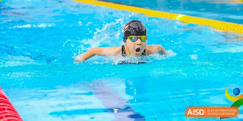 Huili School Shanghai student competing in a swimming race, performing the breaststroke with a large splash.
