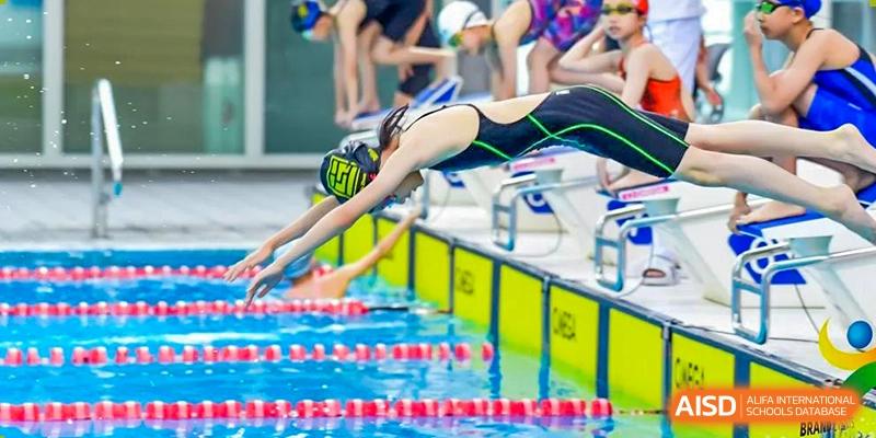 Huili School Shanghai swimmer diving off the starting block at the beginning of a competitive swimming event.
