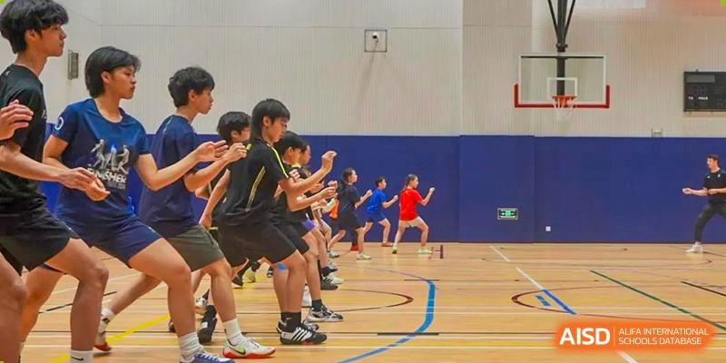 Students from Huili School Shanghai participating in indoor physical education (PE) drills or group warm-ups on a basketball court.