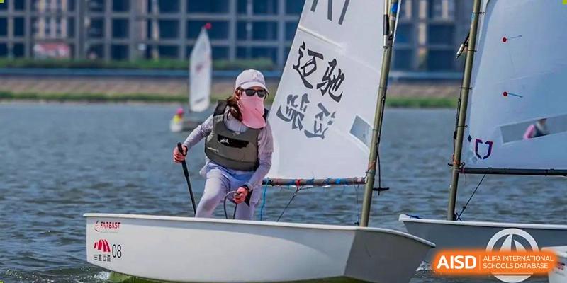 A Huili School Shanghai student in a life vest sails a small dinghy during a water sports activity.