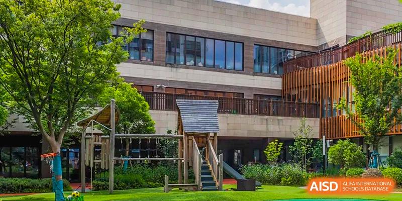 The modern building exterior and natural wooden playground area at Huili School Shanghai.