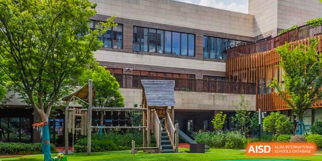 The modern building exterior and natural wooden playground area at Huili School Shanghai.