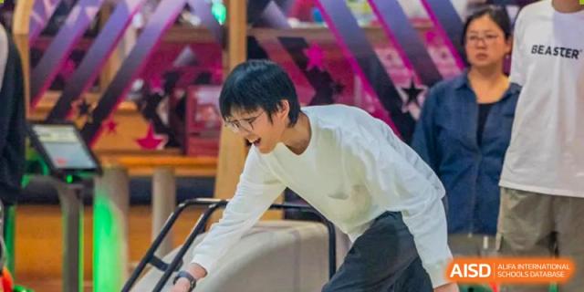 Huili School Shanghai student in a white shirt bending down during an indoor leisure or club activity.