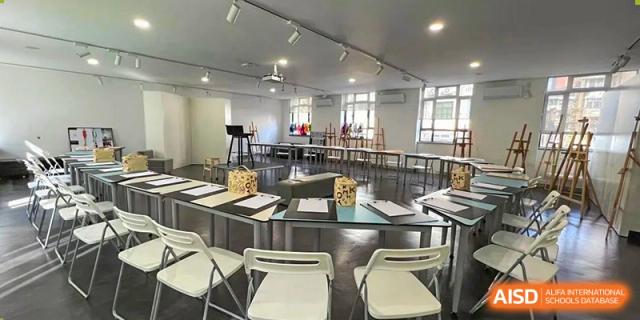 An empty classroom or art studio with tables and chairs set up at Yew Wah International Education School of Shanghai Gubei.