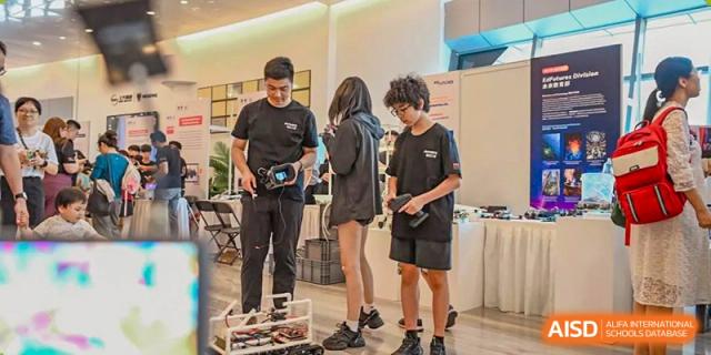 Students working on a project with robotics or technical equipment at a booth at Yew Wah International Education School of Shanghai Gubei.
