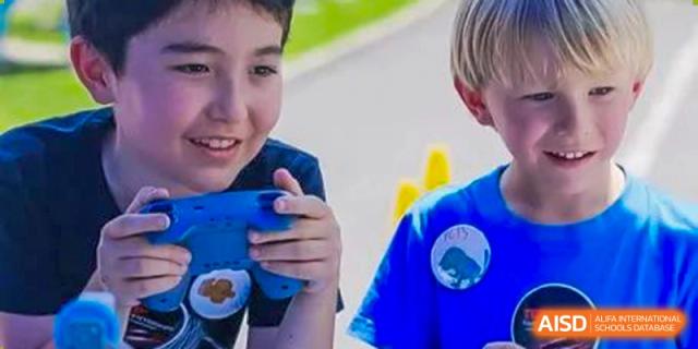 A young student smiling and holding a blue object during a class activity at Yew Wah International Education School of Shanghai Gubei.