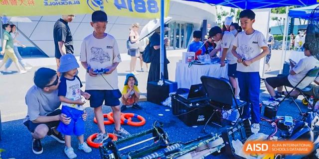 Students at an outdoor event booth with various hands-on activities at Yew Wah International Education School of Shanghai Gubei.