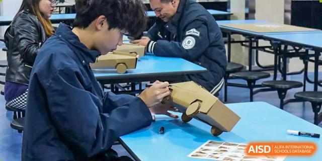 Students working together to build a model car out of cardboard at Yew Wah International Education School of Shanghai Gubei.