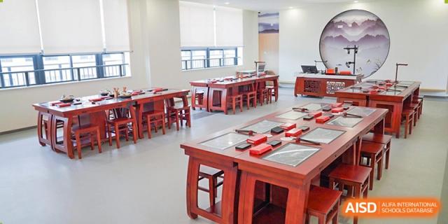 An empty classroom with several wooden tables and chairs in a traditional style at Shenzhen Foreign Languages GBA Academy.