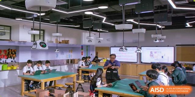 A group of students at Shenzhen Foreign Languages GBA Academy engaged in a hands-on project with a teacher in a modern lab or workshop.