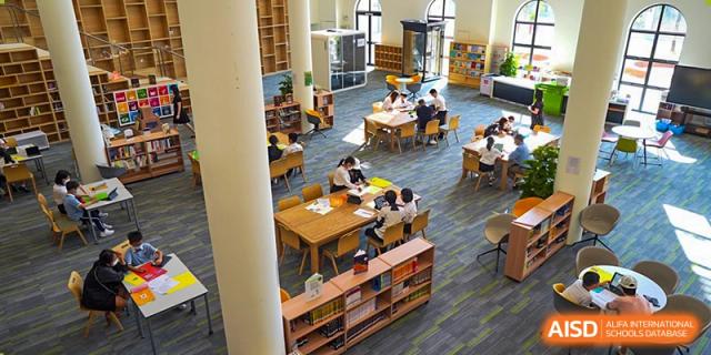 An aerial view of students at Shenzhen Foreign Languages GBA Academy reading and studying at tables in the library.