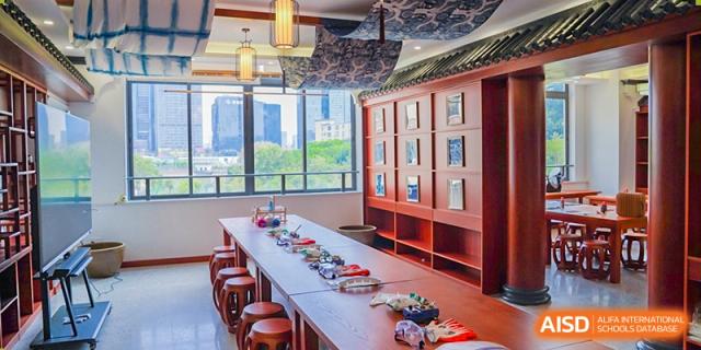 A long wooden table with art supplies and chairs in a classroom at Shenzhen Foreign Languages GBA Academy.