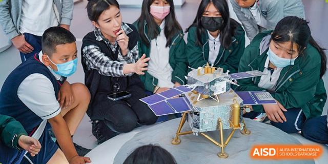 A group of female students at Shenzhen Foreign Languages GBA Academy wearing face masks and working on a solar-powered model.