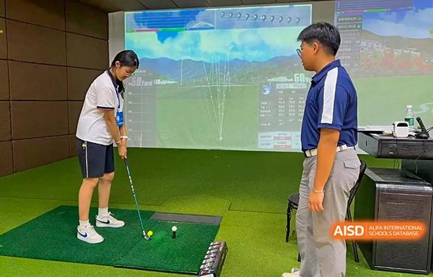 A student at Shenzhen Foreign Languages GBA Academy practicing golf with an instructor on an indoor simulator.
