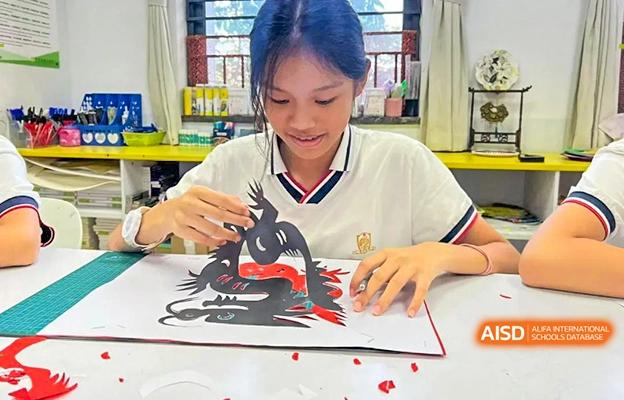 A female student at Shenzhen Foreign Languages GBA Academy is focused on a paper-cutting art project.