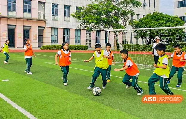Students at Shenzhen Foreign Languages GBA Academy playing soccer on a green sports field.
