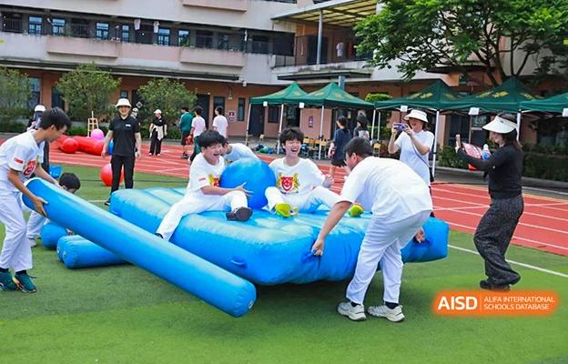 Students at Shenzhen Foreign Languages GBA Academy participating in a fun, inflatable obstacle course on a field.