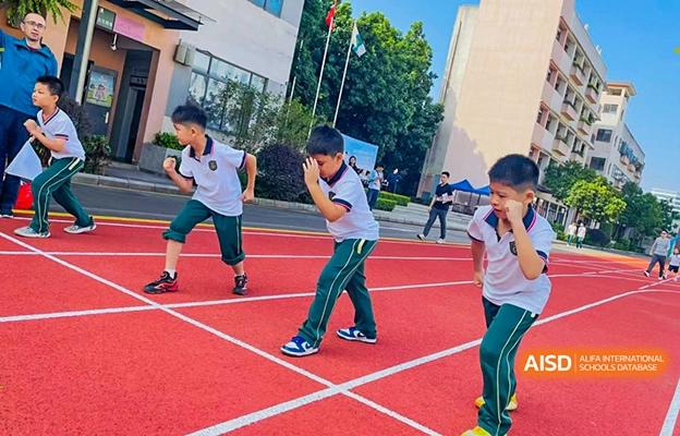 Students at Shenzhen Foreign Languages GBA Academy participating in a race or sports activity on a red track.