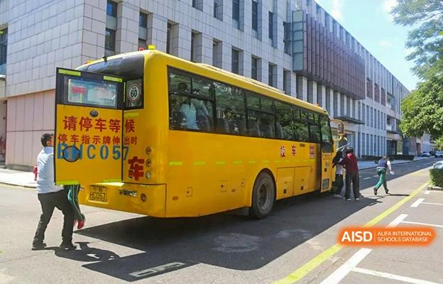 A bright yellow school bus parked outside a building at Shenzhen Foreign Languages GBA Academy.