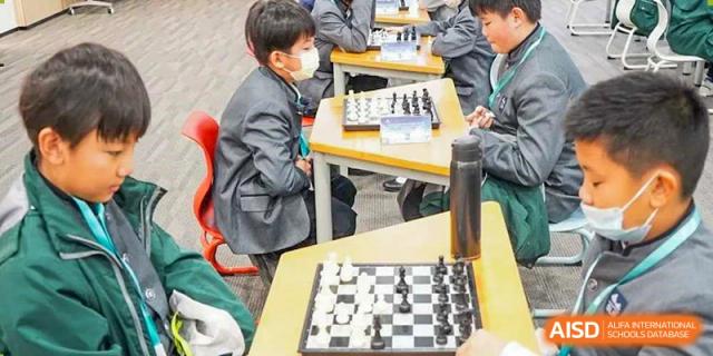 Two students at Shenzhen Foreign Languages GBA Academy playing a game of chess in a classroom.