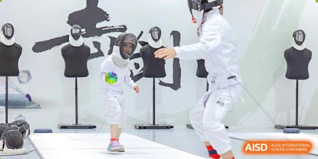 A student at Shenzhen Foreign Languages GBA Academy in protective gear practicing fencing with a coach.
