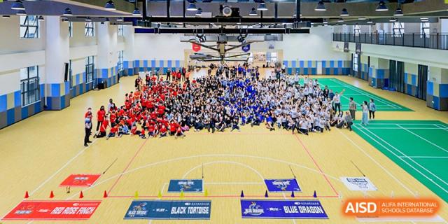 An aerial view of a large group of students at Shenzhen Foreign Languages GBA Academy gathered on a basketball court for an event.