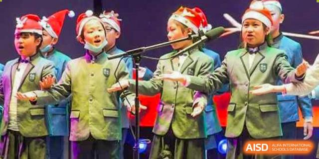 A student at Shenzhen Foreign Languages GBA Academy singing into a microphone on a stage during a performance.