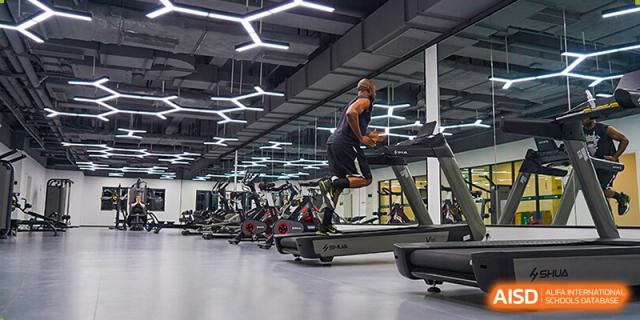 A male student at Shenzhen Foreign Languages GBA Academy working out on a treadmill in a modern gym.