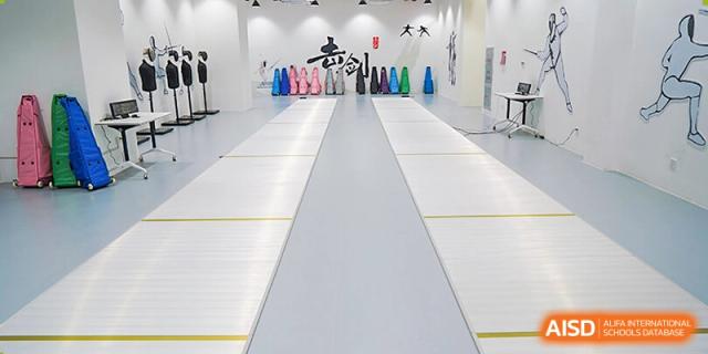 An empty fencing hall with fencing foils lined up against the wall at Shenzhen Foreign Languages GBA Academy.