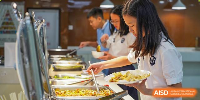 Students and a teacher at Shenzhen Foreign Languages GBA Academy serving themselves from a buffet in the cafeteria.