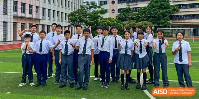 A group of male and female students from Maple Leaf International Academy Shenzhen, dressed in their uniforms, are posing for a photo outdoors.