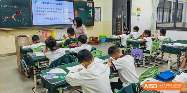 A teacher from Maple Leaf International Academy Shenzhen is helping a student with his work in a classroom.