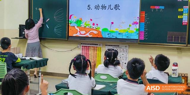 A student from Maple Leaf International Academy Shenzhen is raising her hand in a classroom to ask a question.