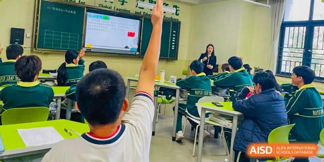 A student from Maple Leaf International Academy Shenzhen is raising his hand to answer a question in class.
