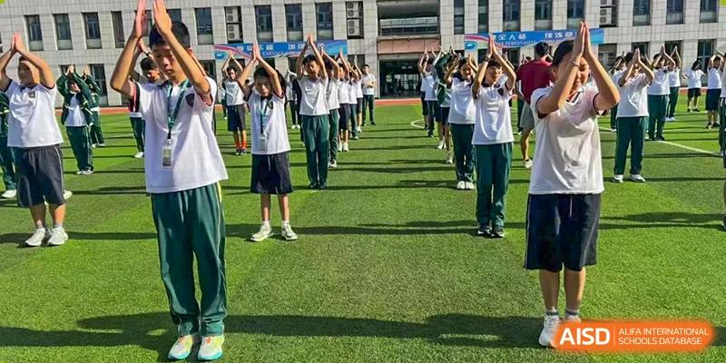 Students from Maple Leaf International Academy Shenzhen are participating in an outdoor morning exercise on the school field.