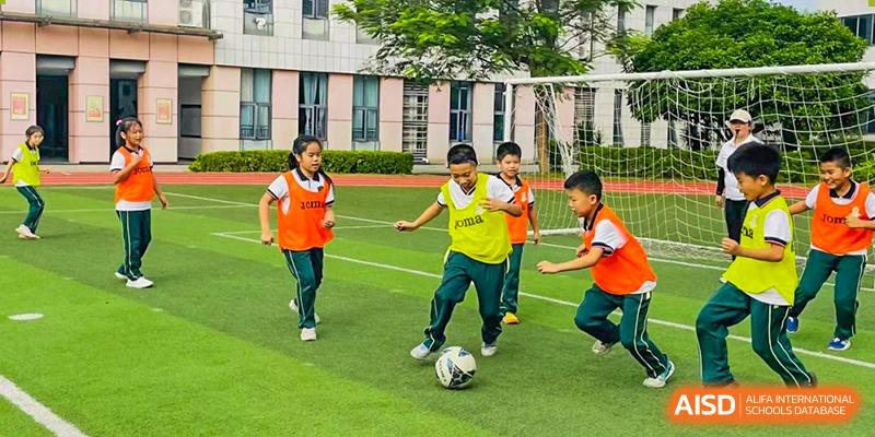 Students from Maple Leaf International Academy Shenzhen are playing soccer on a grassy sports field.