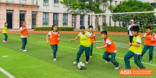 Students from Maple Leaf International Academy Shenzhen are playing soccer on a grassy sports field.
