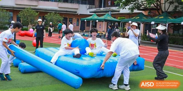 Students from Maple Leaf International Academy Shenzhen are playing on a large inflatable slide outdoors.