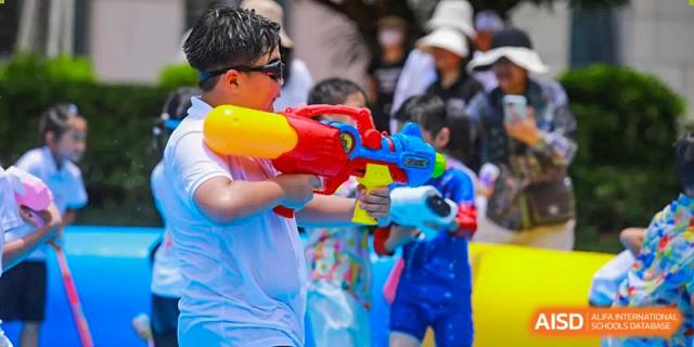 A student from Maple Leaf International Academy Shenzhen is holding a water gun and spraying water at others.