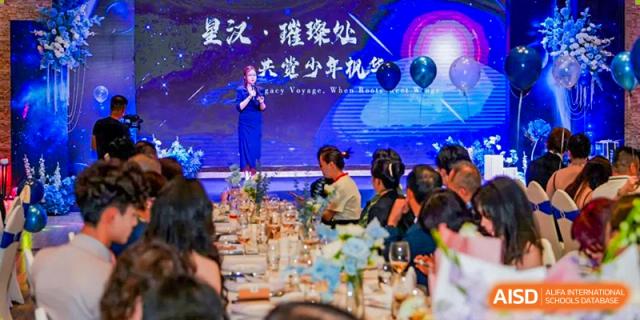 A performer from Maple Leaf International Academy Shenzhen is standing on a stage, singing to an audience.