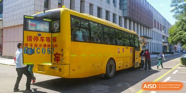 The yellow school bus of Maple Leaf International Academy Shenzhen is parked outside the school building.
