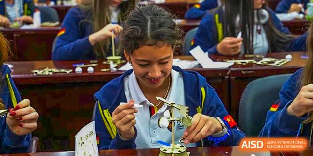 A young female student from HuZ Deutsche Schule Shenyang smiling while conducting a science experiment in class.