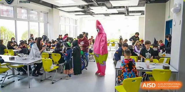 A student from HuZ Deutsche Schule Shenyang dressed in a pink bunny costume, standing among other students in a classroom.
