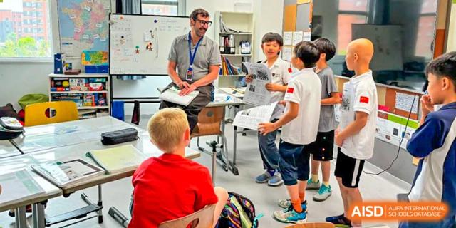 Students from HuZ Deutsche Schule Shenyang gathered around a desk to watch a technology demonstration.