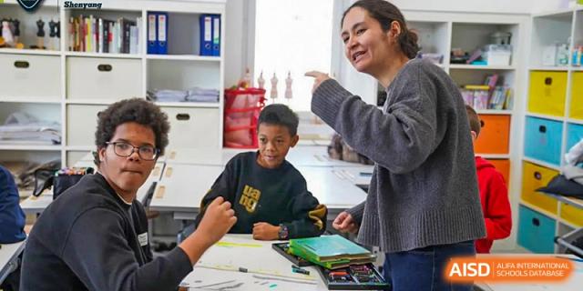 A teacher at HuZ Deutsche Schule Shenyang leaning over to help a student with a school project.