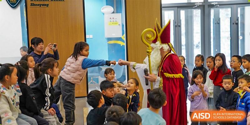 A group of young students is watching a man dressed as St. Nicholas at HuZ Deutsche Schule Shenyang.